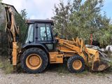 a backhoe of a tractor that is parked on the side of the road