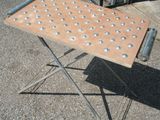 une petite table percée de trous, posée sur le trottoir