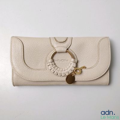 beige leather purse with a gold ring and a keychain on a white table