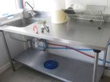 a stainless steel sink and a metal shelf in a kitchen
