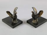 une paire de serre-livres en bronze représentant des oiseaux, posés sur des socles en marbre noir
