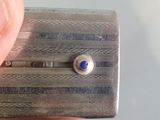 a person holding a small silver object with a blue stone in it