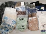 de nombreux vêtements de toutes sortes, rangés dans des sacs posés sur la table