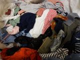 a pile of clothes that is on a bed