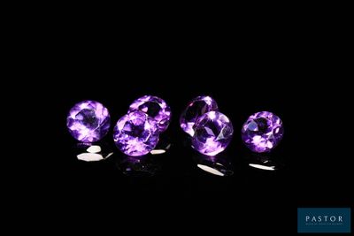 un groupe de pierres précieuses violettes posées sur une surface noire
