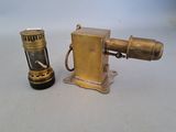 a small brass lighter next to a lighter on a table