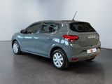 the back end of a grey car in a room with a white wall