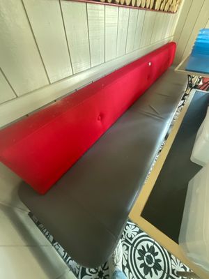 un banc sur lequel est posé un coussin rouge, dans une pièce