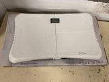 a white electronic scale on a box on the floor