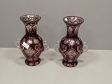 une paire de vases en verre violet posés sur une table blanche
