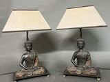 a pair of bronze buddha lamps with shades on them