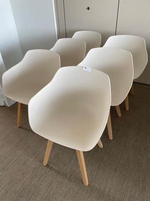 four white chairs are lined up against a wall in a room