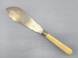 an antique butter knife with a wooden handle on a gray surface