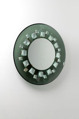 un miroir rond accroché au mur, parsemé de nombreux carrés