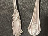 two silver spoons sitting on top of a table next to each other