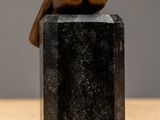 sculpture of a hand resting on top of a black stone block
