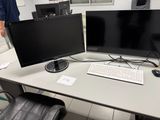 deux écrans et un clavier posés sur un bureau dans une pièce