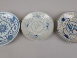 three blue and white plates with designs on them sitting on a table