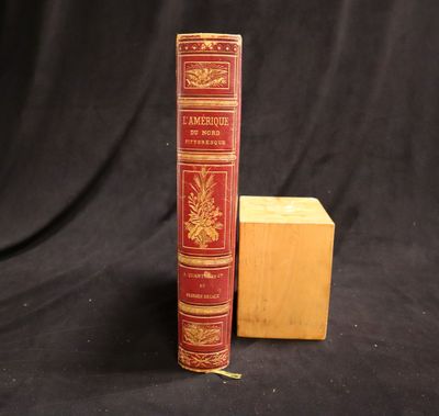 an old book sitting next to a wooden block on a black background