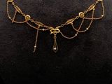 un collier en or orné de perles et de chaînes, posé sur un mannequin