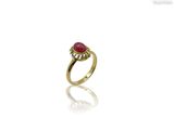 gros plan d'une bague en or avec une pierre rouge