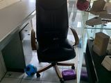 a black office chair sitting in front of a glass desk
