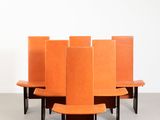 six chaises orange sont disposées en cercle sur un sol en béton