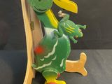 a wooden toy of a green dragon on a skateboard