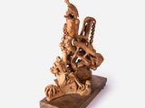 a wooden sculpture of a bird on a stand