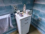 une petite armoire dans un coin d'une salle de bains carrelée de bleu
