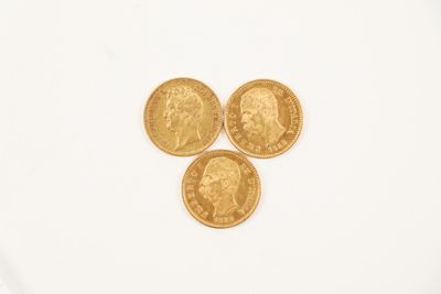 three gold coins sitting on top of each other on a white surface