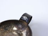 a metal bowl with a handle on a white surface