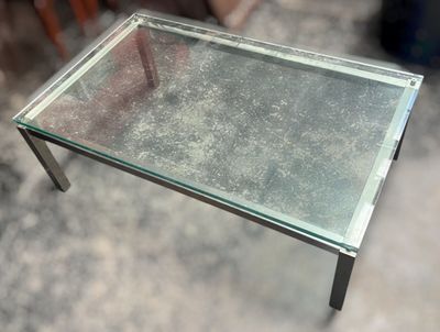 une table en verre avec une base en métal et un plateau en verre