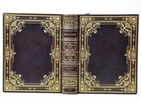 an old book with gold trim and a black cover on a white background