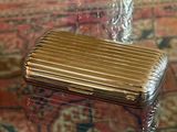a silver cigarette case sitting on a table next to a vase