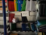 a shelf full of books and binders in a room