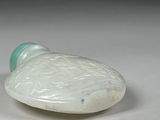 a white and green glass bottle sitting on a white surface