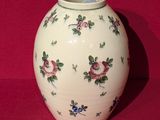 un vase blanc orné de fleurs, posé sur une surface rouge