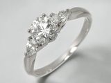 un gros plan d'une bague en diamant à trois pierres sur fond blanc