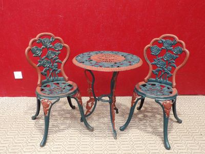 deux chaises et une table posées à même le sol devant un mur rouge