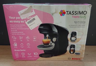 une machine à café encore dans son emballage, posée sur une table à côté d'une tasse de café