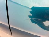 a hand that is holding a cell phone near a car