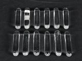 six clear plastic pill caps sitting on top of a black surface