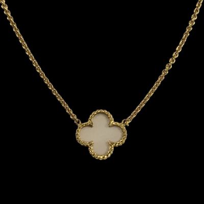 un collier en or orné d'une fleur blanche sur fond noir