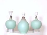 trois vases en verre posés sur une étagère, sur une surface blanche