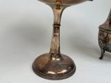 a silver bowl sitting on top of a table next to a silver vase