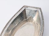 a silver plate with a decorative edge on a white surface
