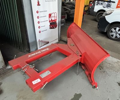 une déneigeuse rouge posée au sol devant un immeuble