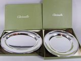 two silver plates in a green box on a white table