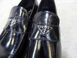 black leather shoes with a prada logo on the side of them